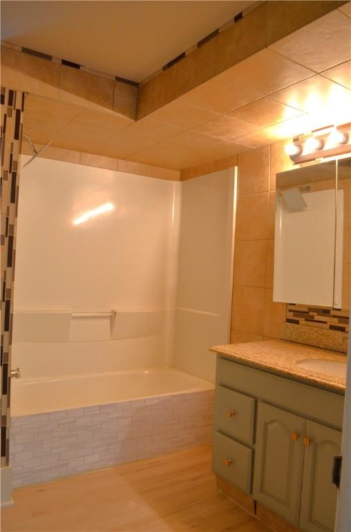 218 S Mercer, Linesville Boro, PA 16424 - full bath with vanity, wood finished floors, tiled shower / bath combo, and decorative backsplash