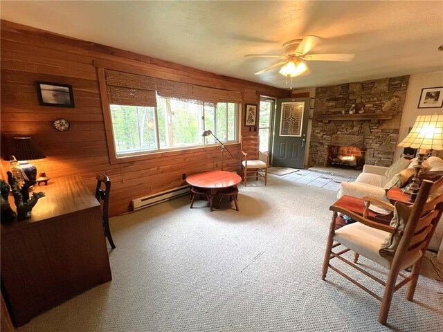 643 Laurel Summit Rd, Jenner Twp, PA 15531 - living area featuring baseboard heating, carpet, wood walls, ceiling fan, and a stone fireplace