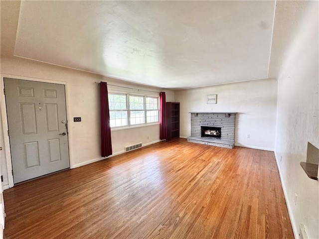 404 Belrose Dr, Rostraver, PA 15012 - unfurnished living room with light wood-style floors, a fireplace with raised hearth, and baseboards