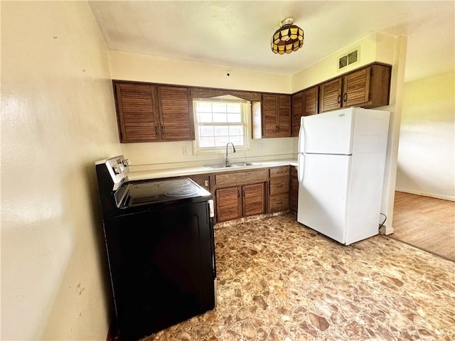 404 Belrose Dr, Rostraver, PA 15012 - kitchen featuring freestanding refrigerator, a sink, electric range, and brown cabinetry