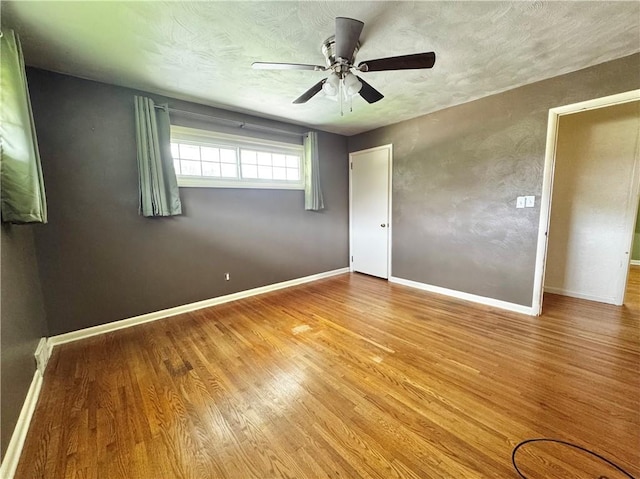 404 Belrose Dr, Rostraver, PA 15012 - empty room with wood finished floors, ceiling fan, baseboards, and a textured ceiling