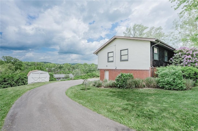 103 Shady Dr, White Twp Ind, PA 15701 - view of side of home with a storage unit, a lawn, an outbuilding, and brick siding