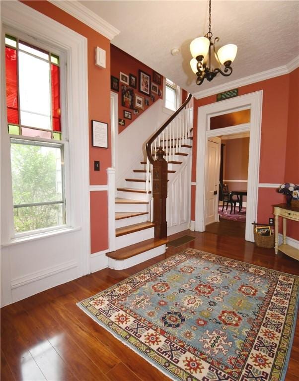 entryway featuring a chandelier, stairway, wood finished floors, and ornamental molding