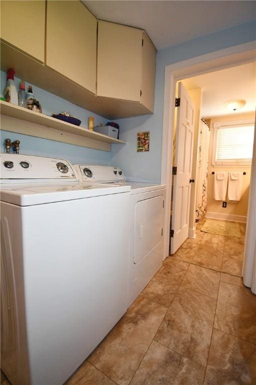 clothes washing area featuring separate washer and dryer, cabinet space, and light tile patterned floors