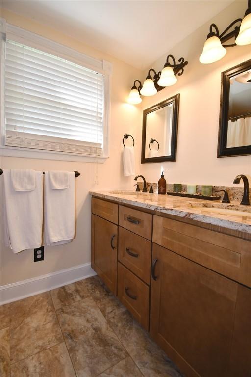bathroom featuring double vanity and baseboards