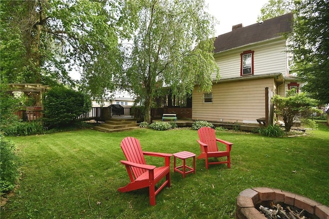 view of green lawn with a fire pit and a wooden deck