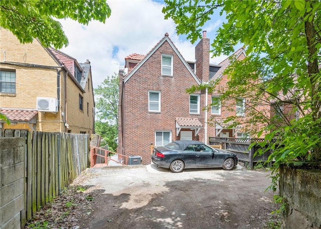 5408 Beacon St, Squirrel Hill, PA 15217 - view of front of property with a chimney, fence, brick siding, a wall mounted AC, and cooling unit