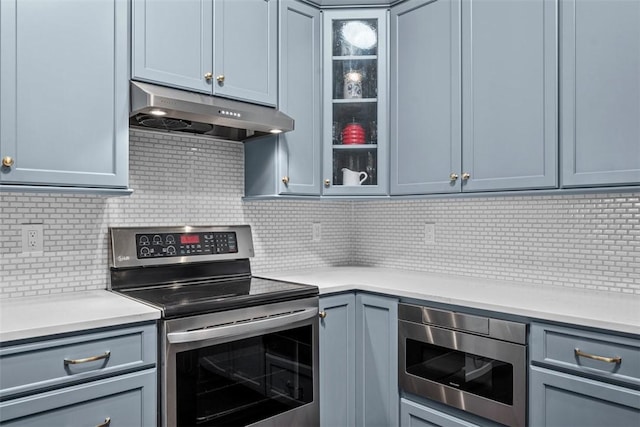 2053 Isleworth, Cranberry Twp, PA 16066 - kitchen with stainless steel appliances, under cabinet range hood, decorative backsplash, light countertops, and glass insert cabinets
