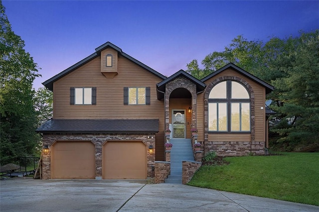 view of front of property with driveway, a front yard, a garage, and brick siding