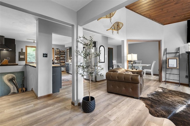 living area with light wood-type flooring, baseboards, and lofted ceiling