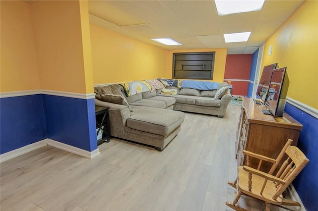 living room with a drop ceiling, wood finished floors, and baseboards