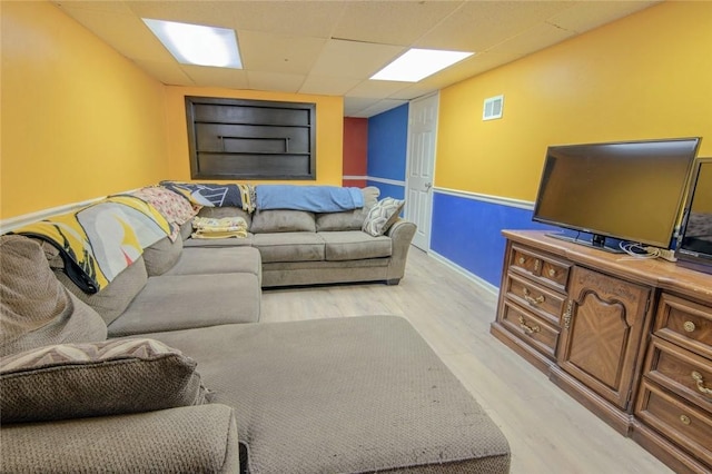 living area with light wood-style floors and a paneled ceiling