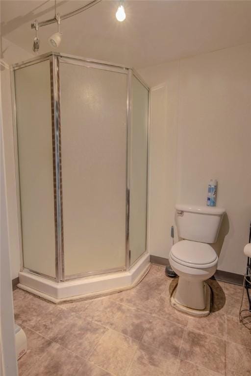 full bath featuring a stall shower, toilet, and baseboards