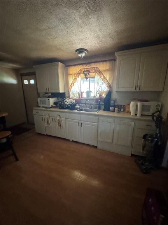 300 N Ave, Midway, PA 15060 - kitchen with a textured ceiling, white cabinets, a sink, light countertops, and wood finished floors