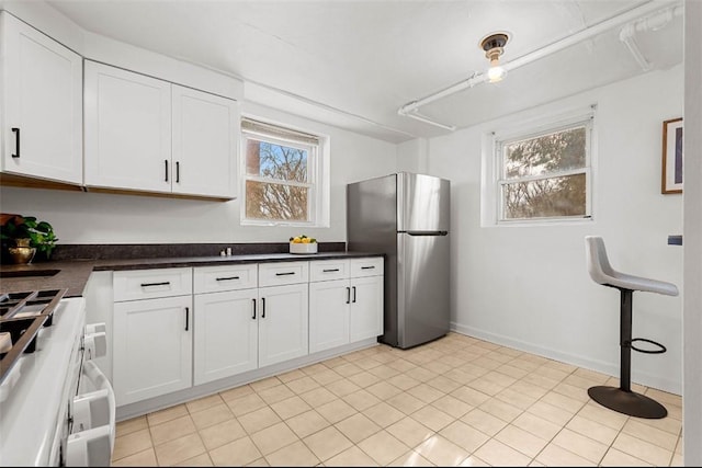 101 Lawncroft Ave Unit A7, Mt Lebanon, PA 15228 - kitchen with freestanding refrigerator, stove, dark countertops, white cabinetry, and baseboards
