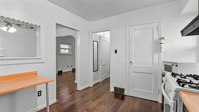 427 W Warrington Ave, Beltzhoover, PA 15210 - kitchen with arched walkways, white appliances, dark wood-style floors, light countertops, and exhaust hood