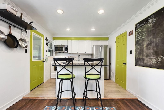 932 Woodbine St, Stanton Heights, PA 15201 - kitchen featuring appliances with stainless steel finishes, white cabinets, crown molding, a breakfast bar, and light wood-style floors