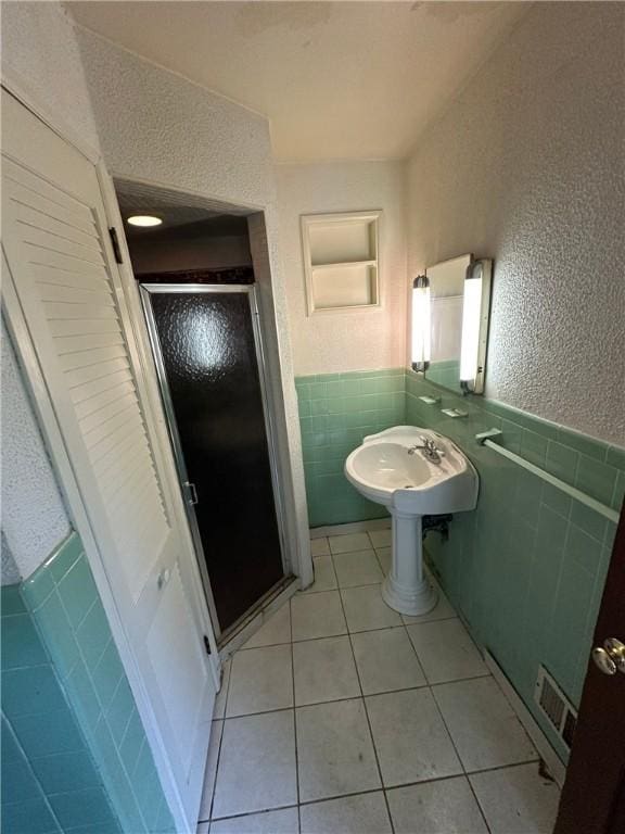 2905 Blackridge Ave, Penn Hills, PA 15235 - full bathroom with tile walls, a shower stall, tile patterned flooring, a wainscoted wall, and a textured wall