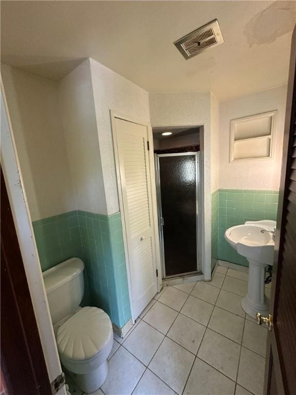 2905 Blackridge Ave, Penn Hills, PA 15235 - bathroom featuring tile walls, tile patterned flooring, a stall shower, a wainscoted wall, and toilet