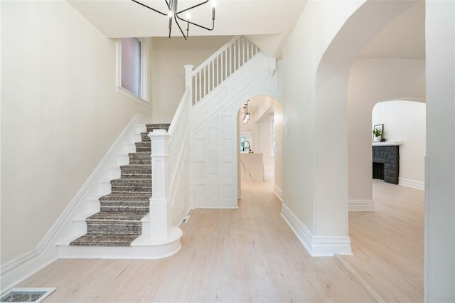 5415 Black St, East Liberty, PA 15206 - stairs with arched walkways, wood finished floors, a towering ceiling, a chandelier, and a fireplace