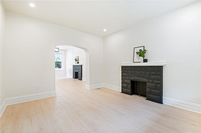 5415 Black St, East Liberty, PA 15206 - unfurnished living room featuring a fireplace, arched walkways, wood finished floors, baseboards, and recessed lighting