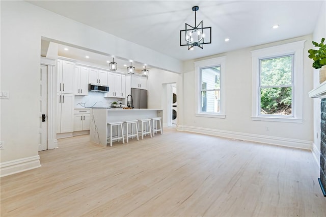 5415 Black St, East Liberty, PA 15206 - kitchen with appliances with stainless steel finishes, stacked washer and clothes dryer, an island with sink, light wood-style floors, and recessed lighting