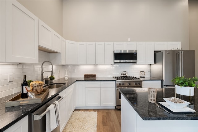 3809 Liberty Ave Unit 403, Lawrenceville, PA 15201 - kitchen featuring appliances with stainless steel finishes, light wood finished floors, white cabinets, dark stone counters, and a high ceiling