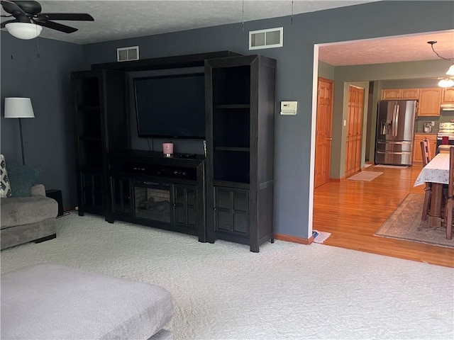101 Pheasant Run Dr, Worth Twp But, PA 16057 - living room featuring ceiling fan, light wood-type flooring, light carpet, baseboards, and a textured ceiling