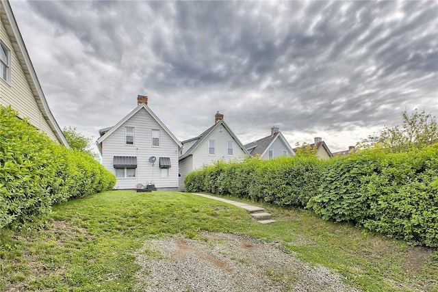 rear view of house with a chimney and a yard