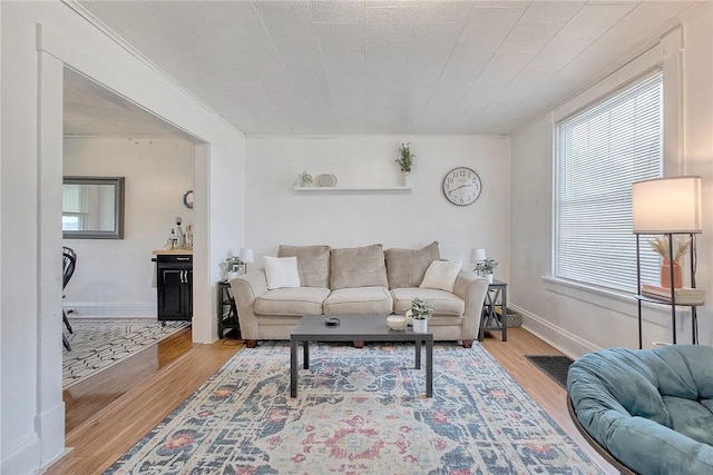 living room with ornamental molding, wood finished floors, plenty of natural light, and baseboards