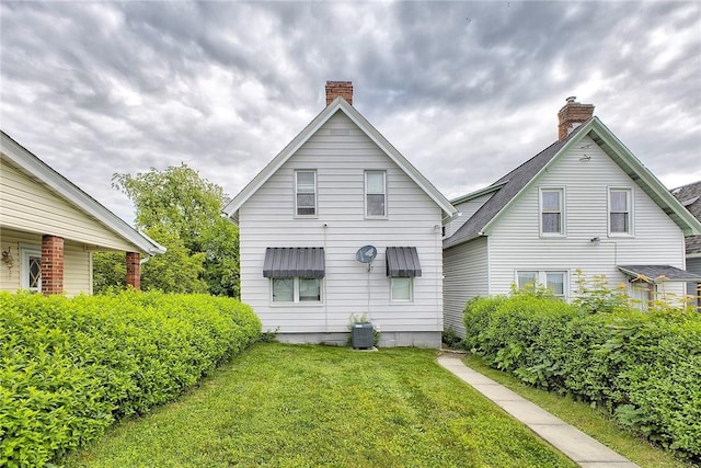 rear view of house featuring a lawn, a chimney, and cooling unit