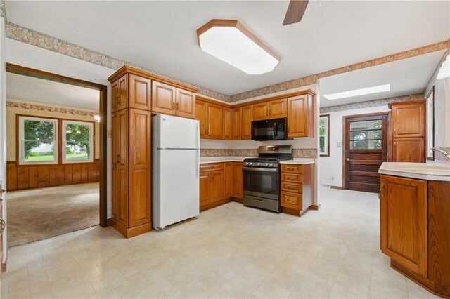 2703 Conway Wallrose Rd, Economy, PA 15005 - kitchen with freestanding refrigerator, stainless steel gas range oven, black microwave, brown cabinets, and healthy amount of natural light
