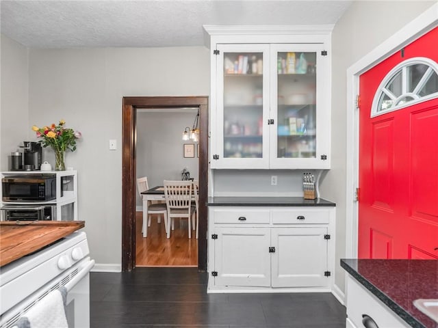 258 Wayne St, Baden, PA 15005 - kitchen with white gas range, dark countertops, white cabinetry, and glass insert cabinets
