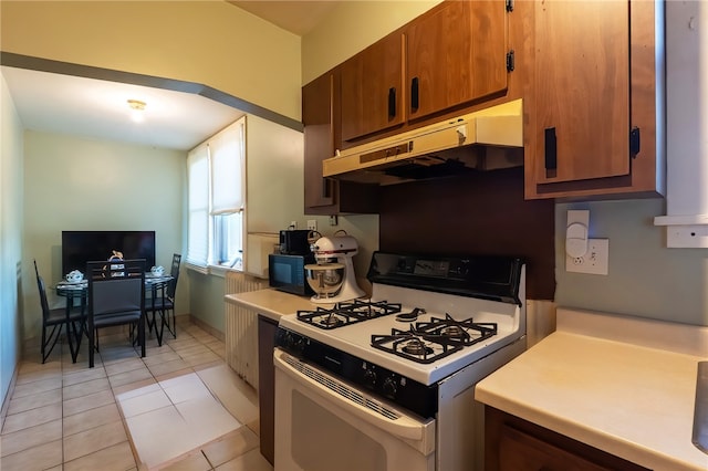 422 Hays Ave, Mount Oliver, PA 15210 - kitchen with white gas range oven, under cabinet range hood, light countertops, brown cabinets, and light tile patterned flooring
