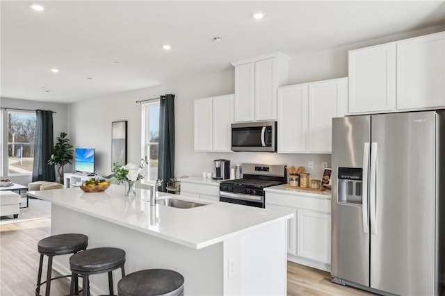 181 Sweetwater Dr, Moon/Crescent Twp, PA 15108 - kitchen with stainless steel appliances, a sink, light wood-style flooring, a kitchen island with sink, and white cabinets