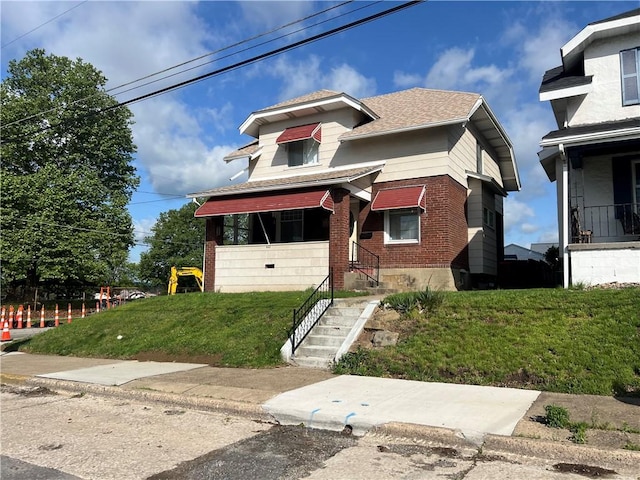 bungalow-style house featuring brick siding, a front lawn, and a shingled roof