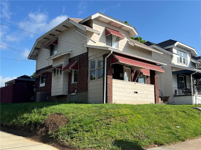view of front of house with cooling unit, brick siding, and a front lawn
