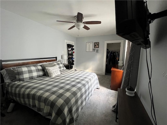 carpeted bedroom with a walk in closet, a closet, a ceiling fan, and baseboards