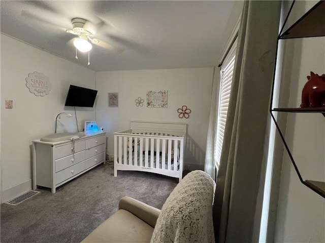 bedroom with carpet, a crib, and ceiling fan