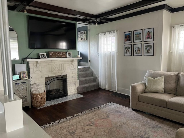 living room with wood finished floors, a fireplace, baseboards, and beam ceiling