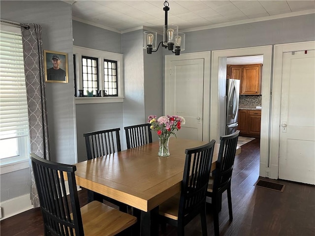 dining room with a chandelier, ornamental molding, and dark wood finished floors