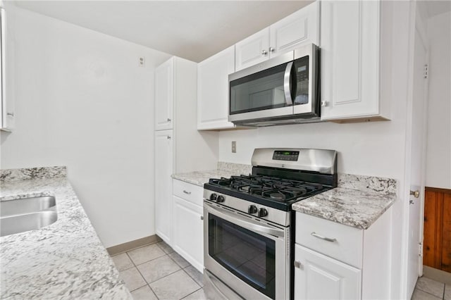119 Hillcrest Dr, Ross Twp, PA 15237 - kitchen featuring appliances with stainless steel finishes, white cabinets, light tile patterned flooring, and baseboards