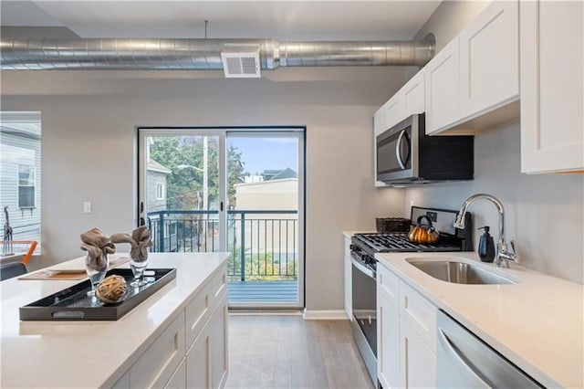 3809 Liberty Ave Unit 308, Lawrenceville, PA 15201 - kitchen with stainless steel appliances, a sink, light wood-style floors, light countertops, and white cabinets