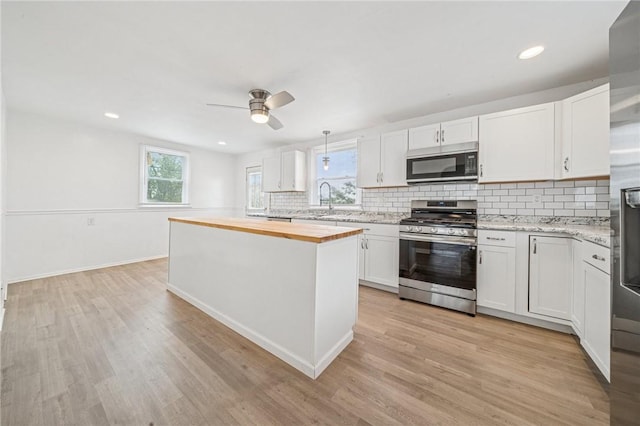 1422 Meadow St, Mckeesport, PA 15132 - kitchen featuring appliances with stainless steel finishes, butcher block counters, light wood-style flooring, backsplash, and recessed lighting