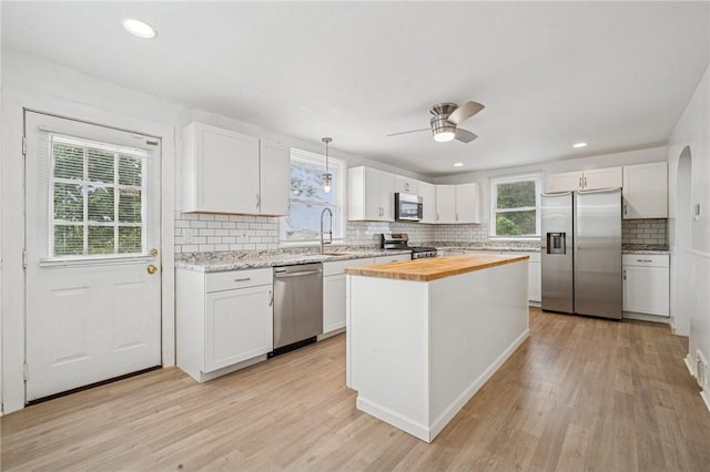 1422 Meadow St, Mckeesport, PA 15132 - kitchen with appliances with stainless steel finishes, wooden counters, decorative backsplash, white cabinetry, and light wood finished floors