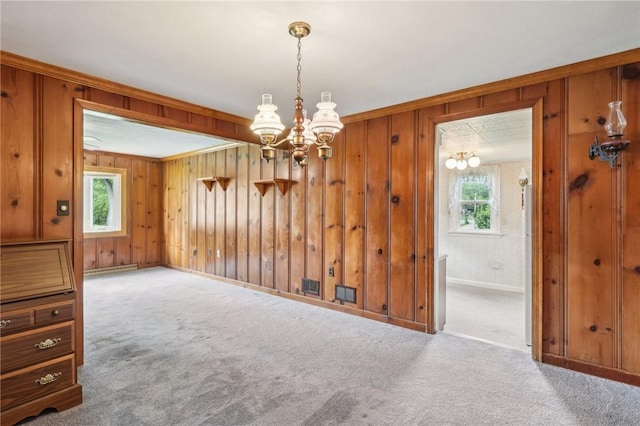 211 Homestead Dr, Middlesex Twp, PA 16059 - unfurnished dining area featuring a chandelier, carpet flooring, wooden walls, baseboards, and crown molding