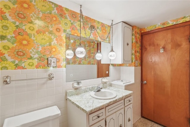 211 Homestead Dr, Middlesex Twp, PA 16059 - bathroom featuring toilet, tile walls, wallpapered walls, vanity, and a wainscoted wall
