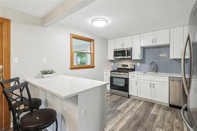 362 Fruitwood Dr, Bethel Park, PA 15102 - kitchen featuring stainless steel appliances, a sink, a peninsula, light wood finished floors, and a breakfast bar area