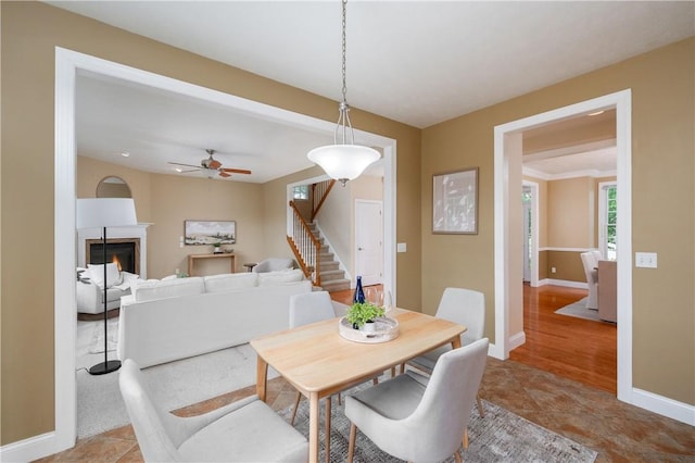 2214 Shannon Mills Dr, Connoquenessing Twp, PA 16053 - dining area with stairs, ceiling fan, baseboards, and a glass covered fireplace