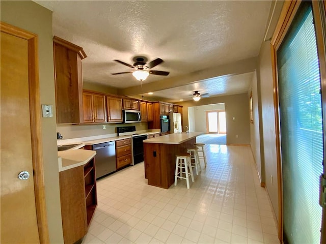 403 Virginia Ave, Harmony Twp Bea, PA 15003 - kitchen featuring appliances with stainless steel finishes, brown cabinetry, a ceiling fan, a textured ceiling, and light countertops